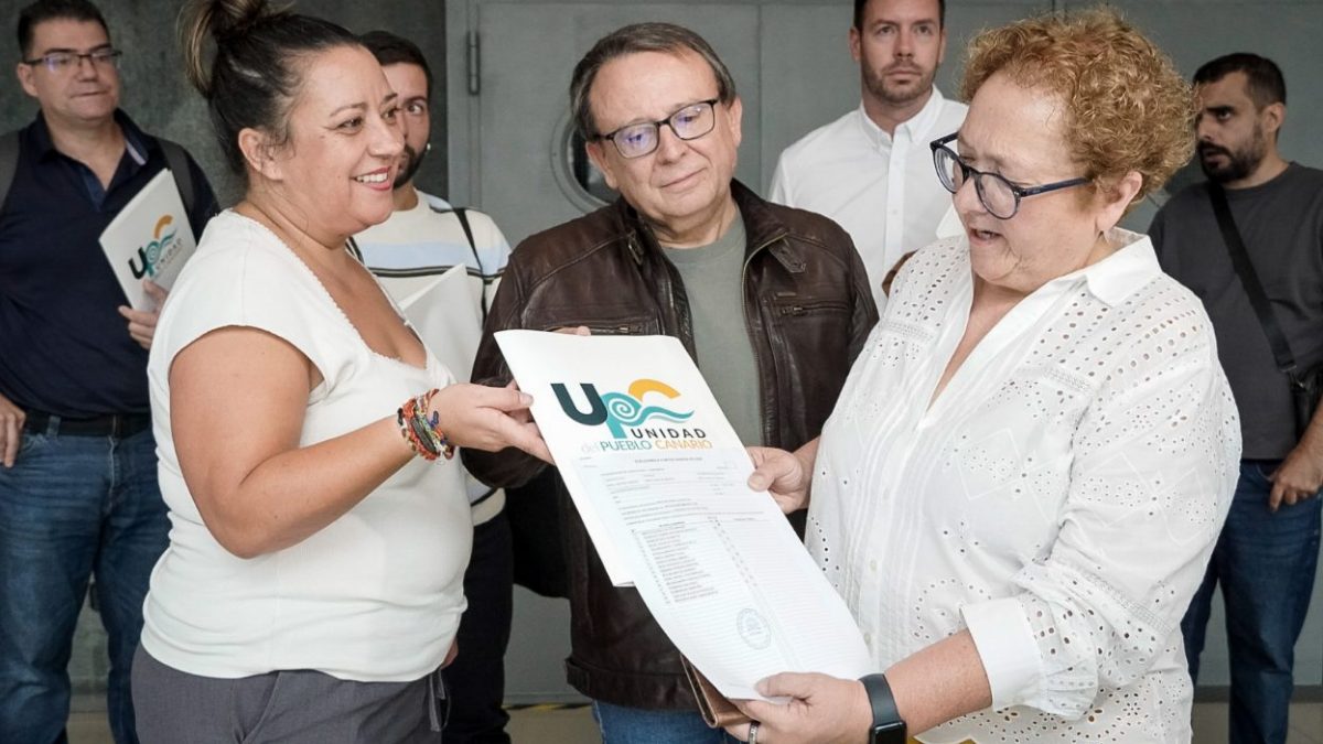 Dos personas sostienen el documento de constitución de UPC con el sello del Registro