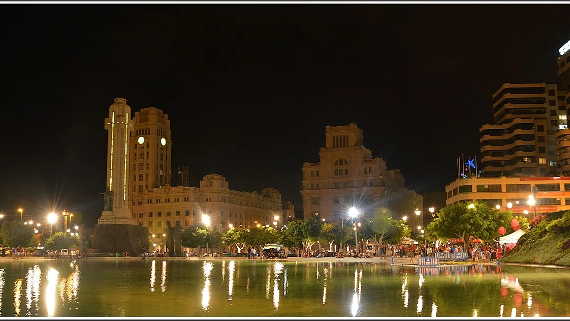 Estanque y jardines de la Plaza de España, en Santa Cruz de Tenerife, iluminados de noche, con edificios al fondo